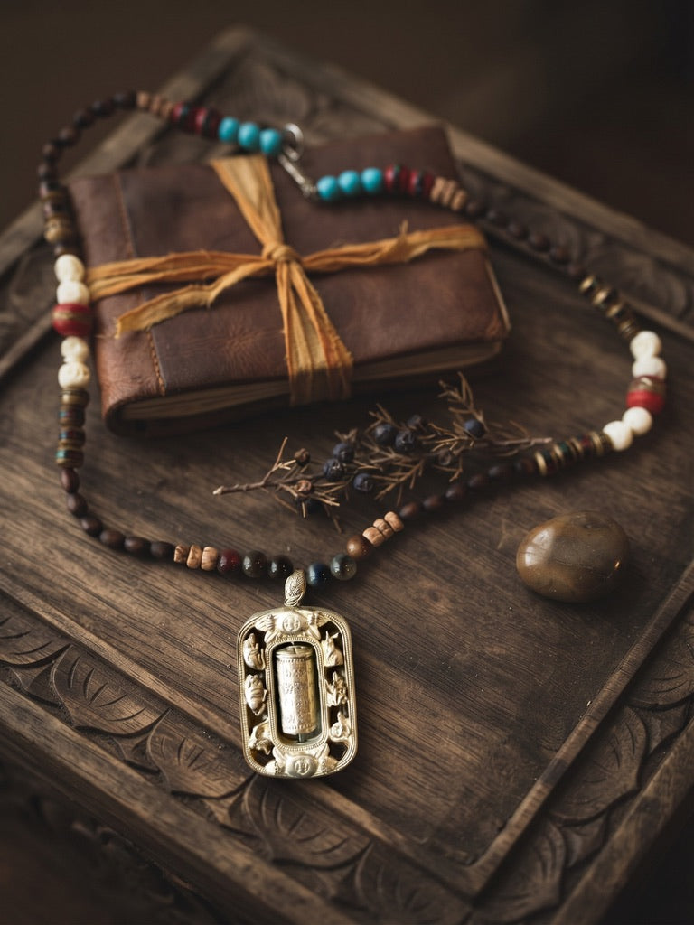 Relics of the Traveler brass prayer scroll necklace on a carved wooden box with leather journal