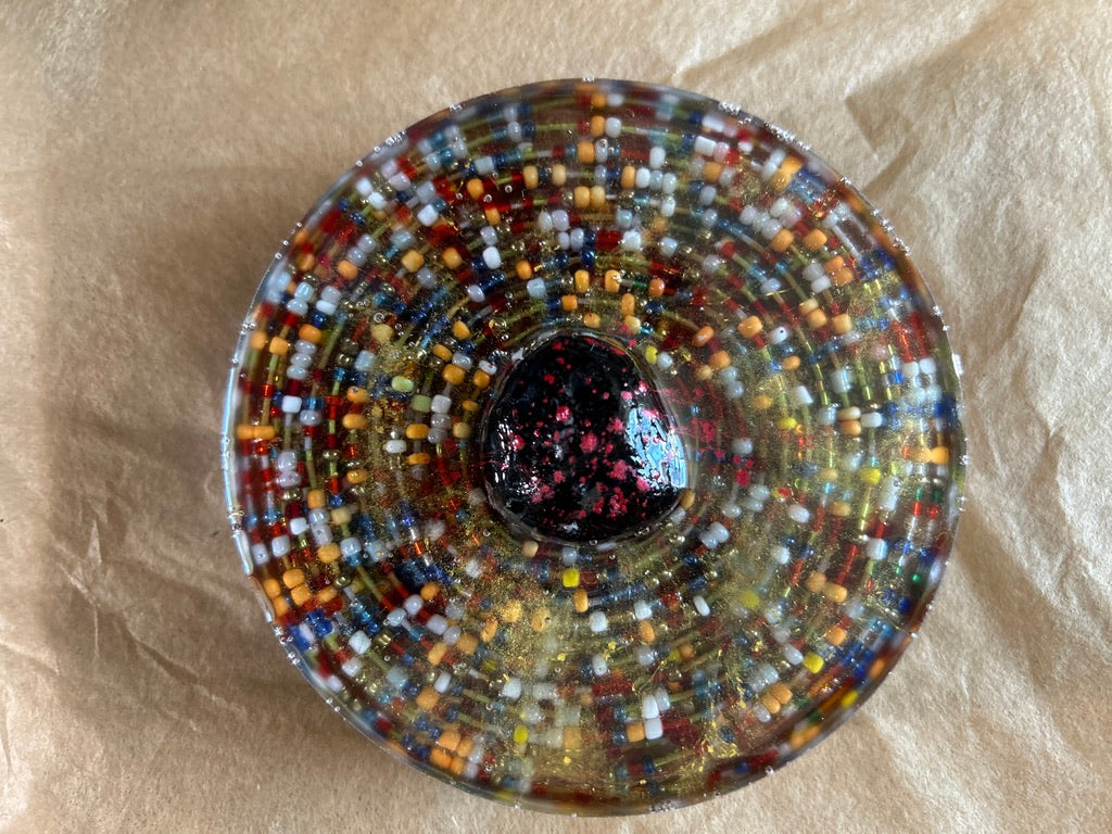 Thousand Beads Concentric Ring Circle Resin Paperweight – Miniature World with thousands of rainbow seed beads in concentric rings and raw obsidian center