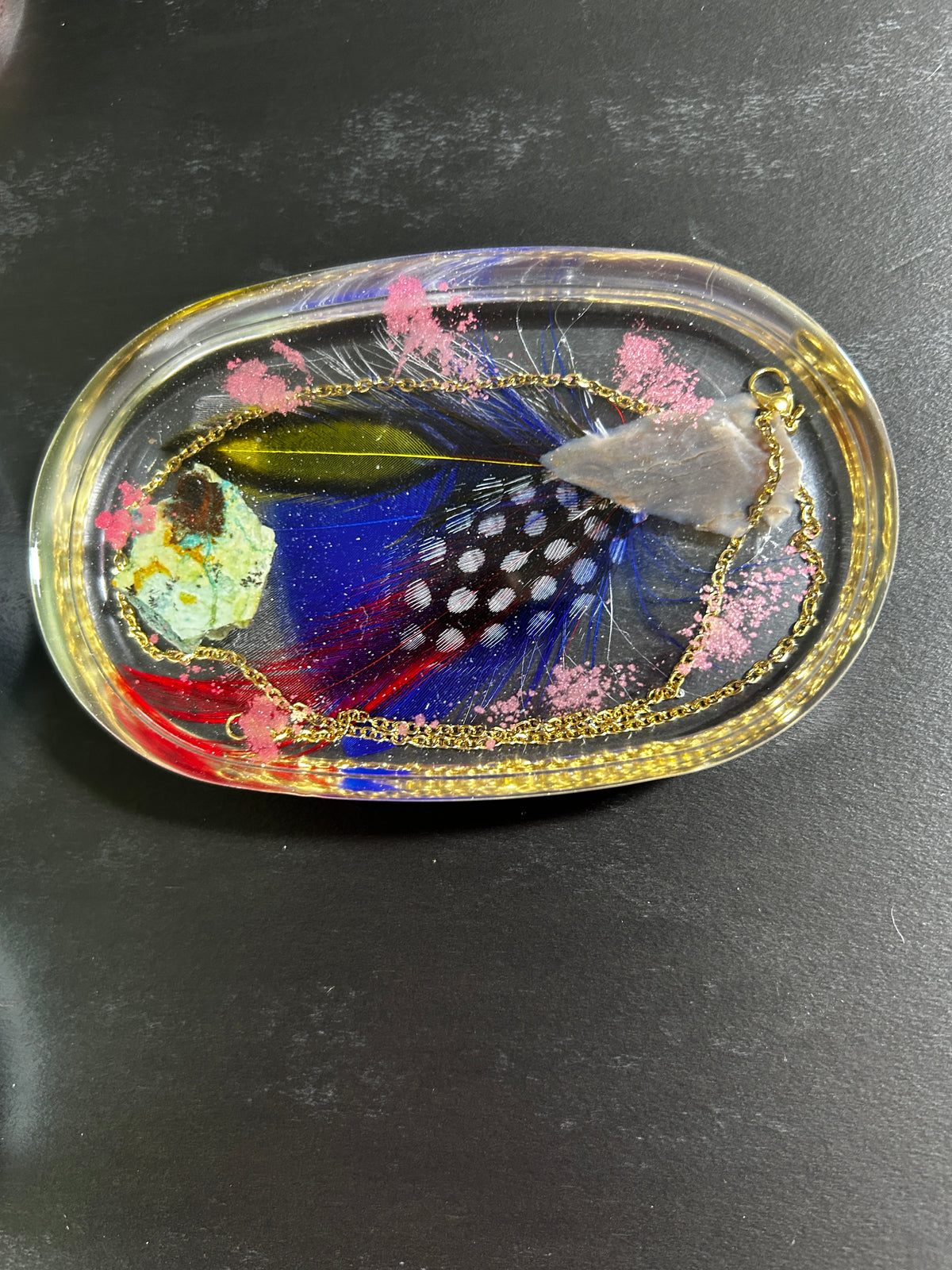 Guinea Fowl Feather, Pink Botanicals & Gold Chain Oval Resin Paperweight – Miniature World with cobalt polka dot guinea fowl feather and crimson feathers in gold-edged clear resin