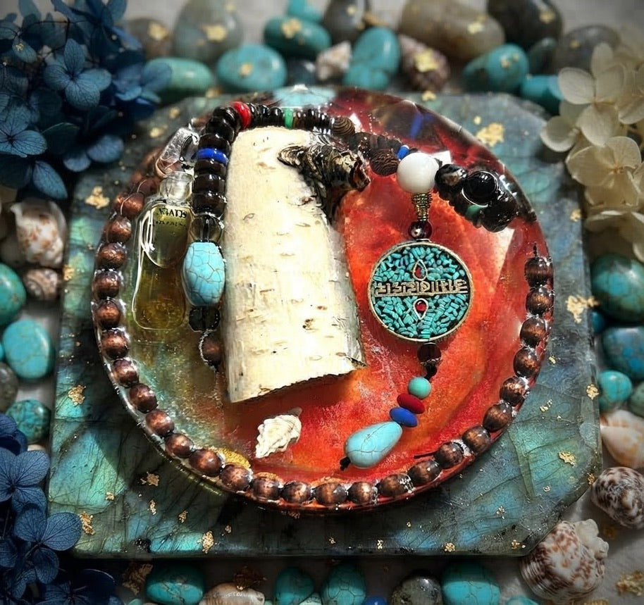 One-of-a-kind paperweight with pale bark, a small bottle, turquoise-colored pendant, and copper-brown bead border in orange-red resin.