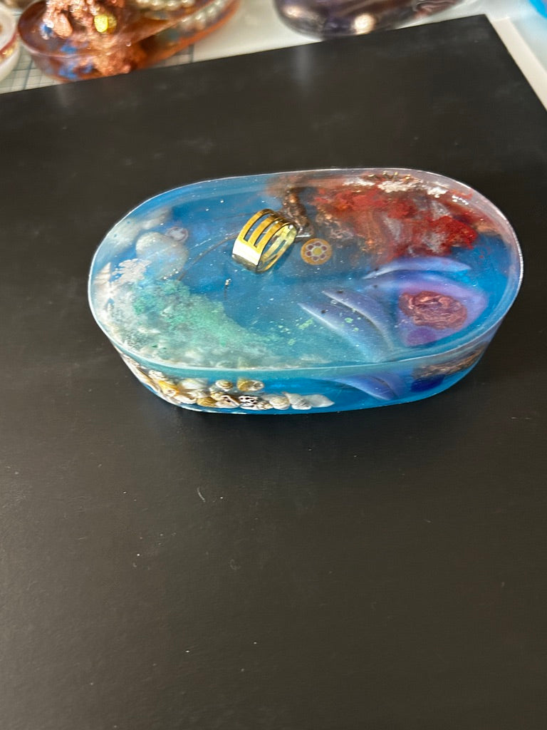 Leaping Porpoise, Coral & Violet Stone Oval Resin Paperweight – Miniature World with porpoises mid-leap through gold hoop in ocean blue resin