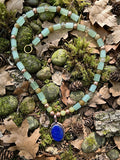 Sea glass and aventurine tube bead necklace with cobalt lapis lazuli silver pendant on forest floor of moss and pine cones