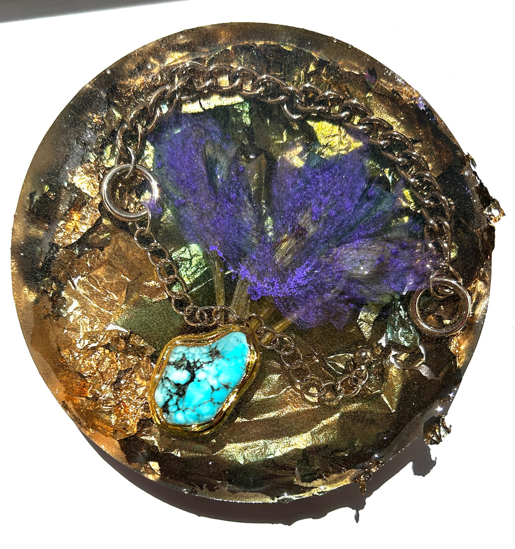 Circular gold resin paperweight with preserved purple botanical fan, raw turquoise pendant, and embedded silver chain