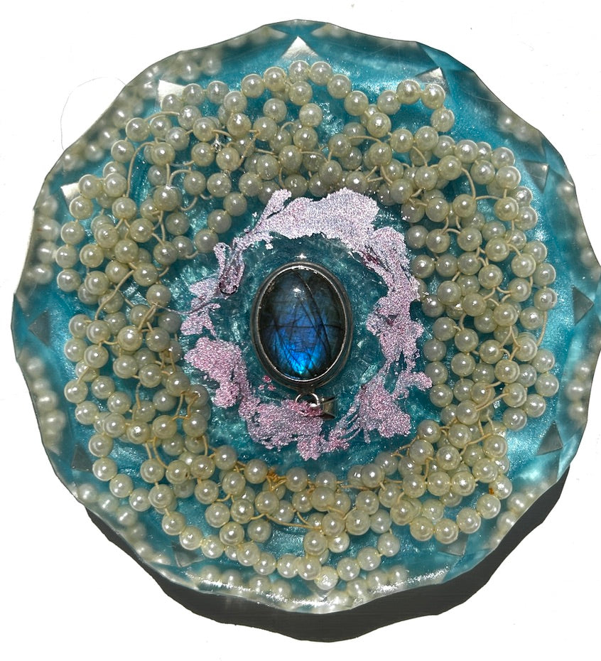 Pearl Mandala Lagoon resin paperweight — overhead view of round disc with faceted scalloped edges showing labradorite oval cabochon in silver bezel surrounded by pink lavender florals and concentric white pearl rope mandala coils in clear aqua teal resin