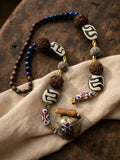 Handcrafted necklace with dzi beads, rudraksha, lapis, chevron trade beads and Kashmiri locket pendant on linen