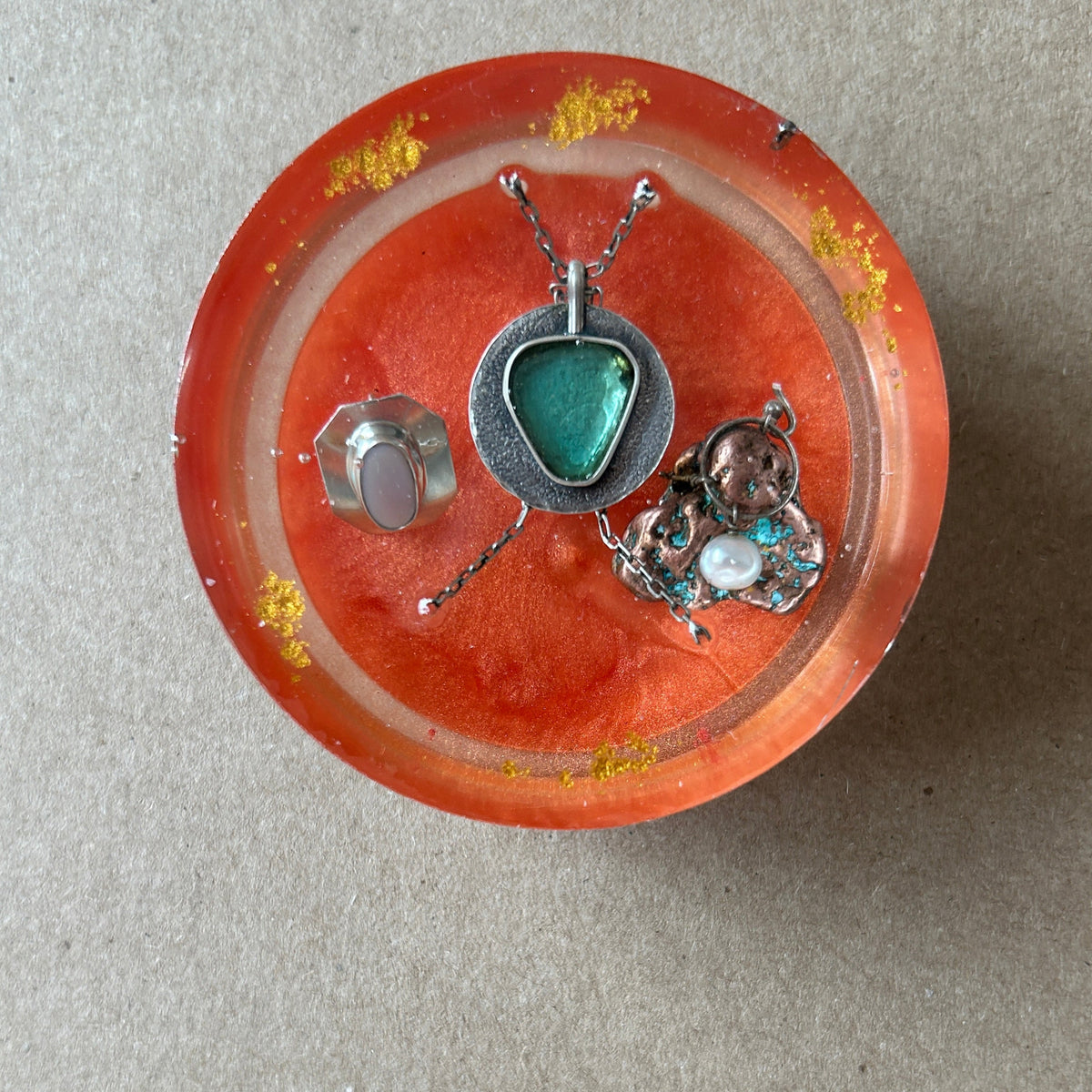 Orange resin paperweight with triangular turquoise-colored pendant, silver-toned settings, chain sections and gold-colored flecks.