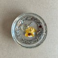 Clear round resin paperweight with yellow flower, silver-toned chain border and fan-shaped metallic charm.