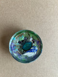 Deep teal oval centerpiece amid green, violet, blue and white textures in rounded resin
