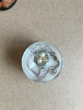 Three pearly beads in a silver-toned nest with looping chains and pale pink-white accents in resin