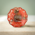 Coral Serenade paperweight with banded oval centerpiece, pearl-like accents and silver-toned chain on a light background