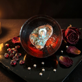 Crimson nebula resin paperweight styled on dark obsidian with garnet chips and warm amber candlelight