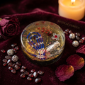 Dark mystical resin paperweight styled on burgundy velvet with garnet chips and candlelit amber lighting
