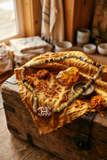 No. 63 The Wanderer's Map necklace on saffron silk with marigold petals and brass compass editorial background